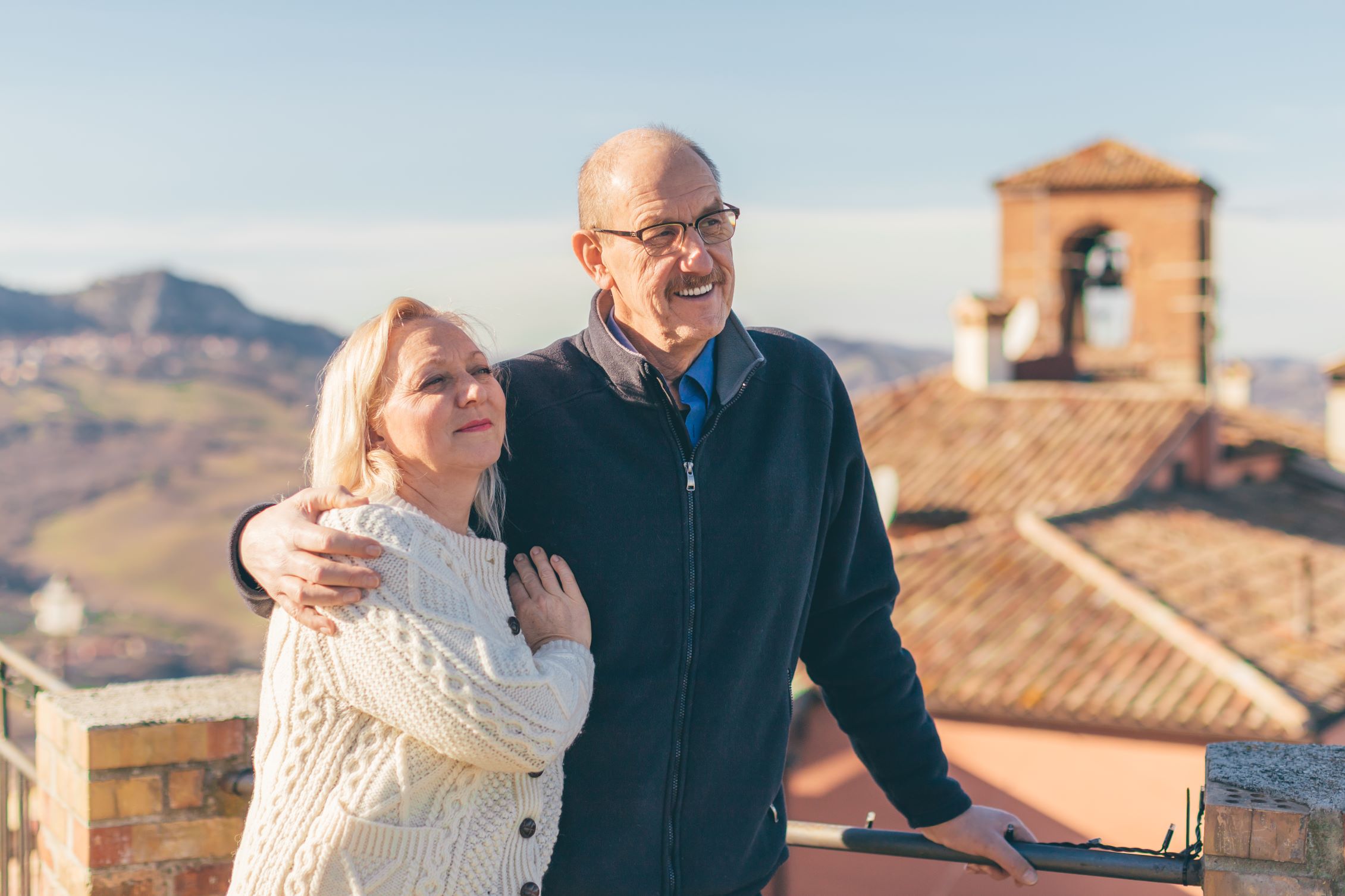 Retired couple embrace and enjoy the view while on vacation in an old Italian town.